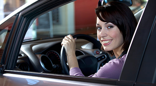 Smiling young woman in her car